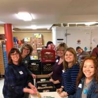 Volunteers pose for a photo together while sorting food.